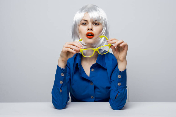 cheerful pretty woman in a white wig sits at the table red lips charm yellow glasses - 写真・画像