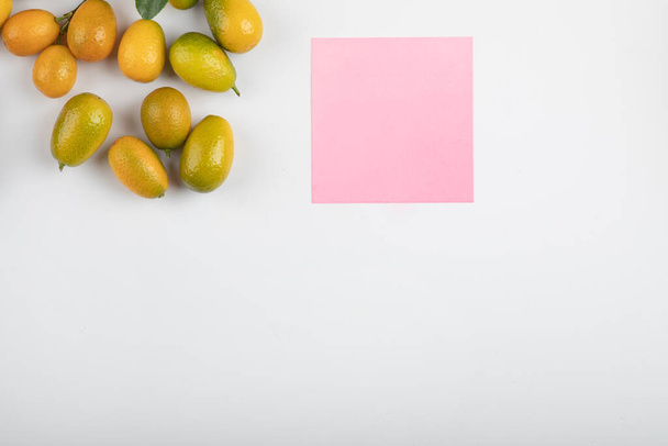 Sombreros amarillos con hojas y papel rosa sobre fondo blanco - Foto, Imagen