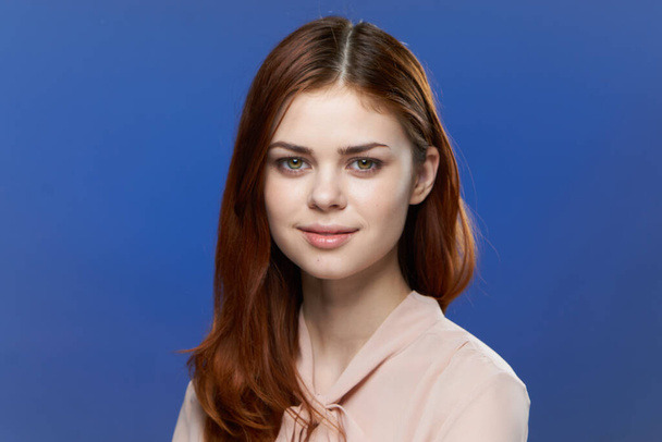 mooie vrouw in roze shirt aantrekkelijke look glimlach blauwe achtergrond model - Foto, afbeelding