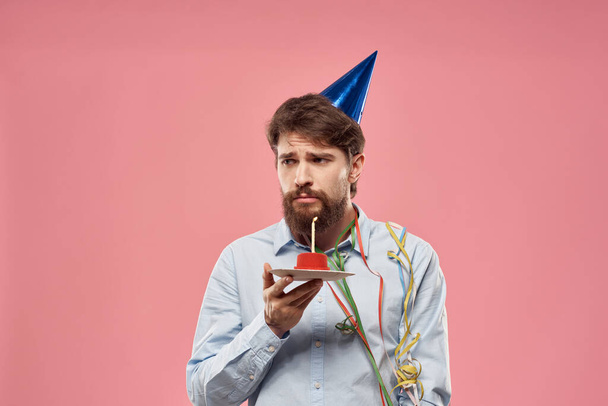 Birthday of a man with a cake and with a candle on a pink background - Foto, immagini