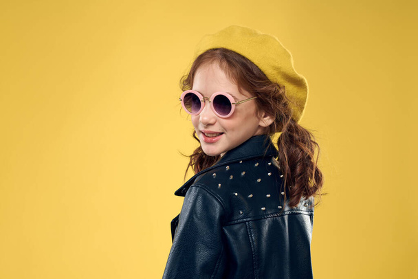 Girl in a yellow hat dark glasses fashionable clothes studio lifestyle childhood - Zdjęcie, obraz