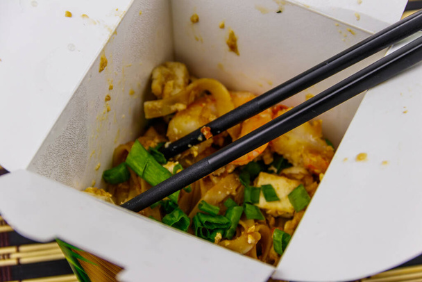 Жареная рисовая лапша с креветками и тофу в открытой картонной коробке. Тайская кухня, Доставка еды - Фото, изображение