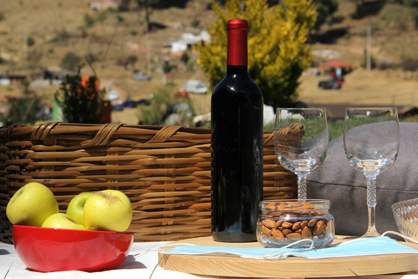 zblízka a zenit pohled na pandemický piknik. koš s vínem, potravinami, ovocem, semeny a ochrannými maskami pro klinické použití - Fotografie, Obrázek