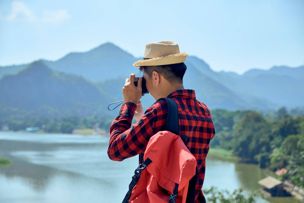 Νεαρός Ασιάτης φωτογράφος ταξιδιών φωτογραφίζει έξω - Φωτογραφία, εικόνα