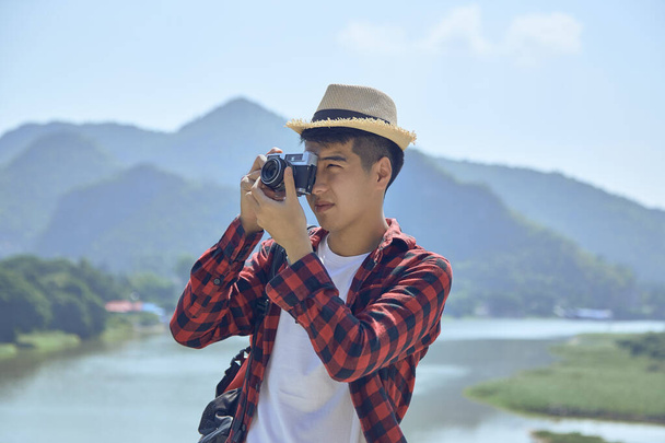 Νεαρός Ασιάτης φωτογράφος ταξιδιών φωτογραφίζει έξω - Φωτογραφία, εικόνα