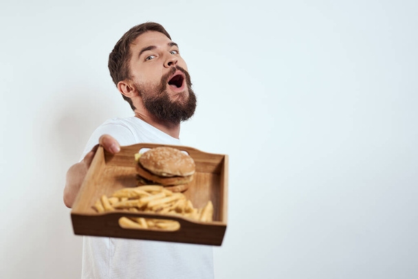 Man met een mok bier fast food dieet voedsel alcohol plezier licht achtergrond - Foto, afbeelding