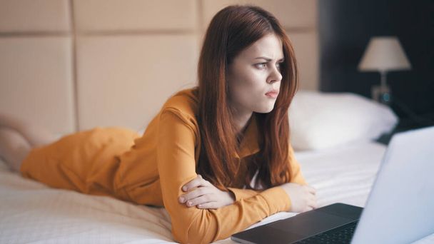 woman lies in bed in front of laptop emotions technology freelance - Photo, Image