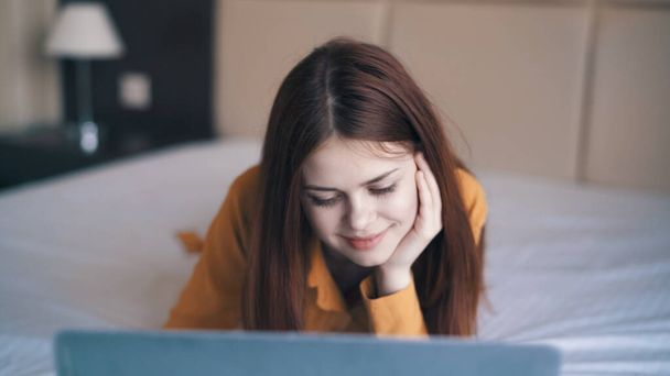 женщина с ноутбуком лежит в постели спальная комната отдыха связи - Фото, изображение