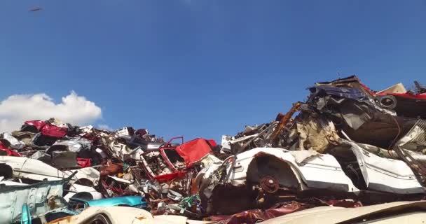 Oogsten van vernielde auto 's op grote schroothoop op zonnige dag in recyclinginrichting - Video