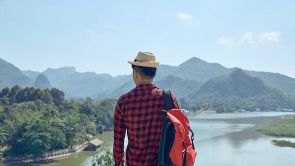 A fiatal ázsiai férfi a hegyekre és folyókra néz. - Fotó, kép
