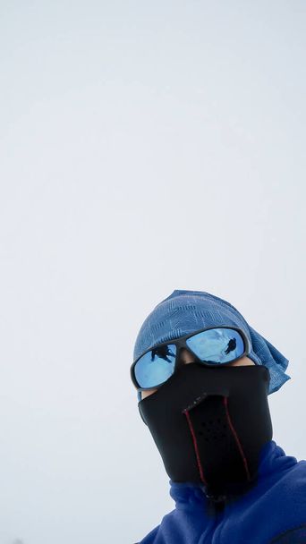 Hiker portrait high at the mountains with mask and glassess looks at the ultimate aim of his trip with fog at background - Photo, Image