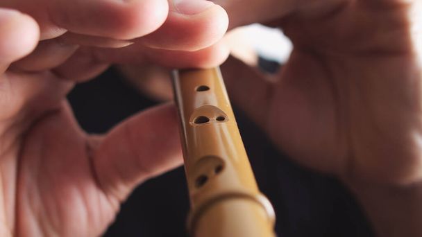 Close-up of a man playing on a recorder on a blur background, wooden wood flute - Фото, зображення