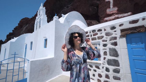 Tourist woman iin dress and hat visiting Saint Nikolaos Orthodox Church located in Akrotiri next to the famous Red Beach at Santorini Island - Fotoğraf, Görsel