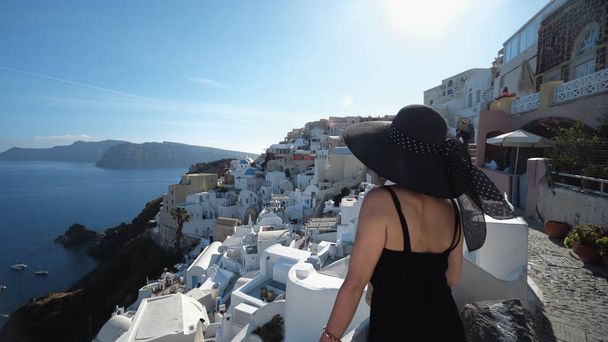 Happy woman dressed elegant smart in black clothes and hat enjoying her holidays on Santorini, Greece - Foto, afbeelding