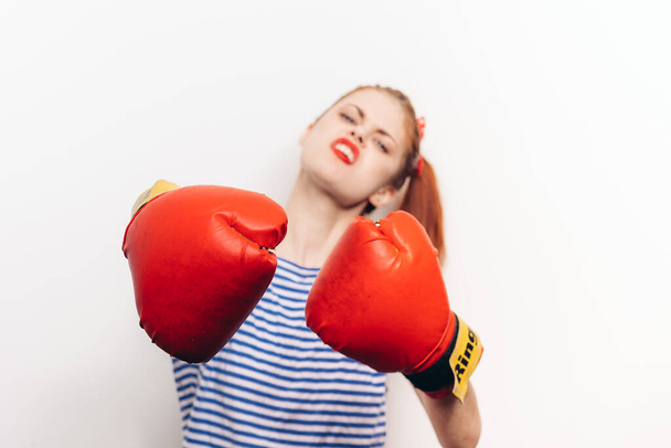 woman boxer in a t-shirt and in red gloves hairstyle makeup light background - Photo, Image