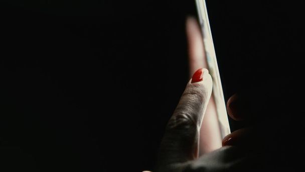 Woman Hand Scroll Playing Smartphone in a Dark - Foto, Imagen