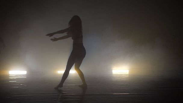 Two young women training their styles of dancing in the smoky studio - Foto, afbeelding
