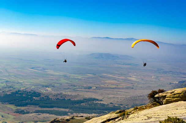 Paragliding flight with blue sky and misty valley - Фото, зображення