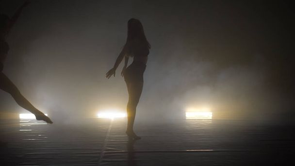 Two young women training their styles of dancing in the smoky studio - Foto, Imagem