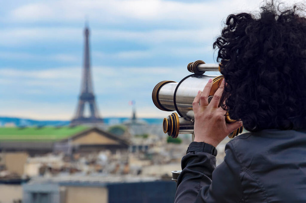 Beautiful brunette woman enjoying view by coin operated binoculars at Garnier Opera and Eiffel Tower in Paris, France - Photo, image