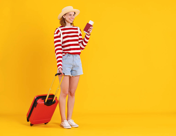 Повна довжина збуджена молодою жінкою-туристкою в повсякденному вбранні і капелюсі з багажем, що дивиться далеко, стоячи біля жовтої стіни і чекаючи польоту під час відпустки
 - Фото, зображення