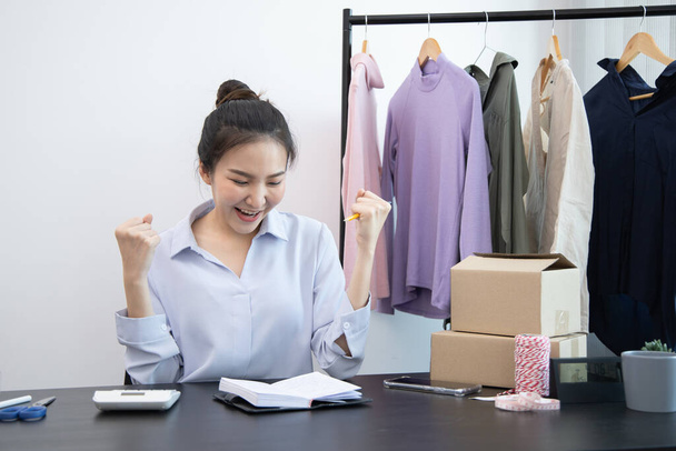 Young Asian woman congratulated and smiled as a large number of customers ordered her clothes online, Feel good, Business of selling clothes on social media or selling online. - 写真・画像