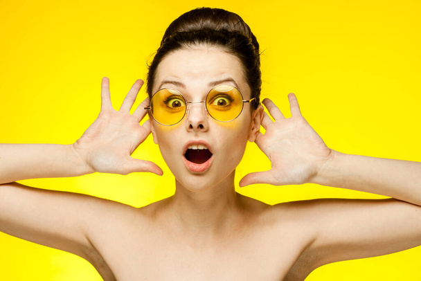donna con spalle nude occhiali gialli mani vicino al viso pelle chiara - Foto, immagini