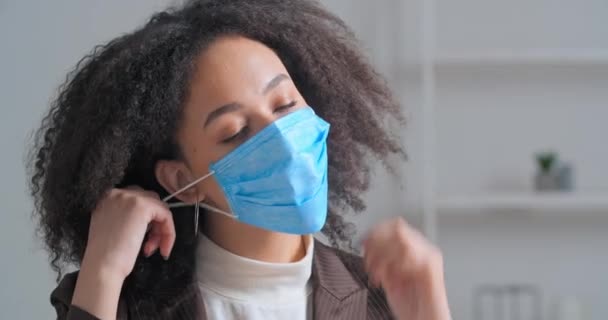 Retrato triste afro-americano encaracolado mulher de negócios estudante tira sua máscara facial médica se sente cansado depois de trabalho duro projeto senta-se no escritório precisa de ar limpo respira profundamente com alívio - Filmagem, Vídeo