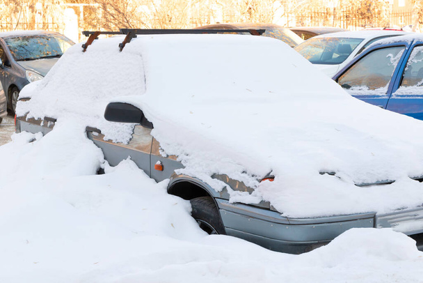 старий покинутий зламаний автомобіль, припаркований біля дороги під великим шаром снігу в холодний зимовий день
 - Фото, зображення