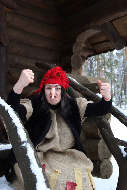 Baba Yaga cerca de la cabaña en el bosque de invierno. Cosplay para el cuento de hadas Morozko. - Foto, Imagen