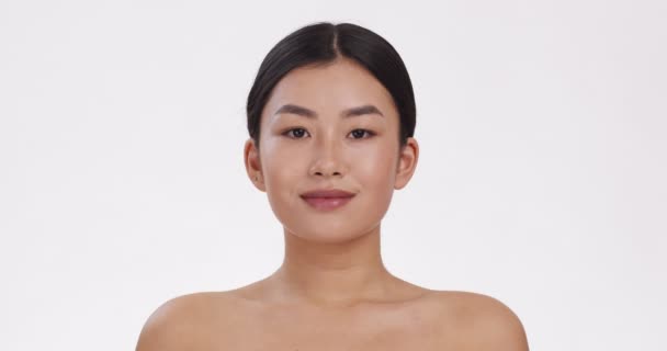 Joven mujer asiática sonriendo a la cámara, demostrando sus dientes blancos perfectos sanos, fondo blanco, cámara lenta - Metraje, vídeo