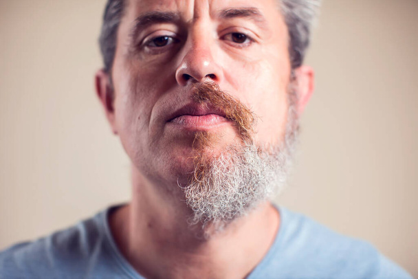 Un retrato de hombre con media barba y pelo sobre fondo marrón - Foto, Imagen