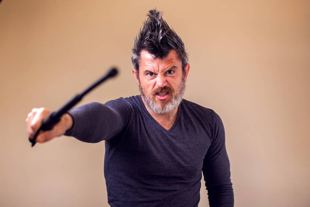 Bearded angry man with tonfa. People and emotions concept - Photo, Image