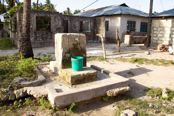 Abastecimiento de agua potable, pozo en aldea africana. Recipiente de plástico bajo el grifo. Problema con el acceso al agua en África. - Foto, Imagen