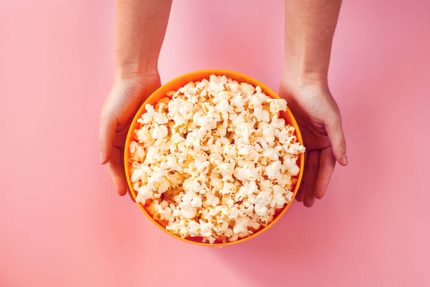 Una ciotola con popcorn su sfondo rosa. Concetto di cibo e intrattenimento - Foto, immagini