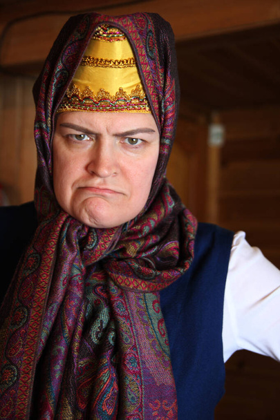 Μια ηλικιωμένη γυναίκα με ρώσικο κουστούμι, με μια γκριμάτσα δυσαρέσκειας στο πρόσωπό της. Cosplay για το παραμύθι Morozko. - Φωτογραφία, εικόνα