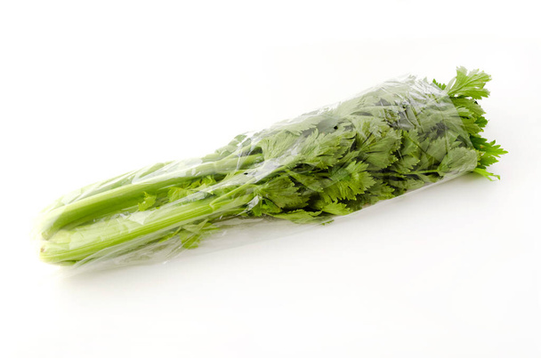 Čerstvý celer zabalený v zábalu na bílém pozadí  - Fotografie, Obrázek