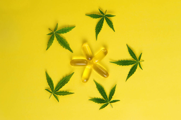 Marihuána olaj, friss levelek. Kannabisznövény sárga háttérrel. Kender rekreáció, orvosi felhasználás, legalizáció.  - Fotó, kép