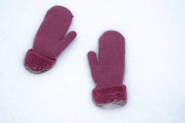 Ζεστά γάντια στο χιόνι. Δύο γάντια βρίσκονται σε λευκό χιόνι πάνω όψη. Παγωμένη εποχή, χιονισμένος χειμώνας.  - Φωτογραφία, εικόνα