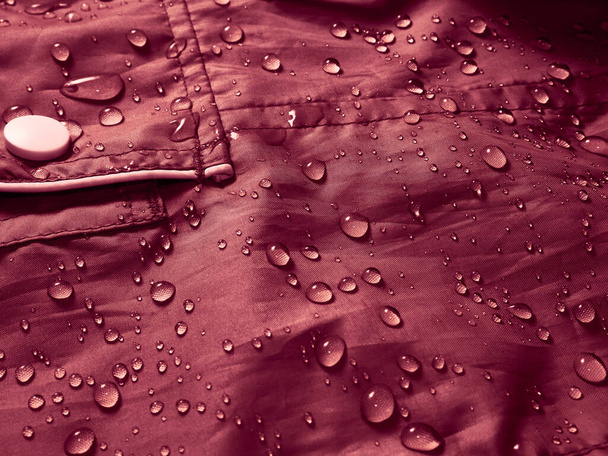 Gocce d'acqua su tessuto membrana impermeabile. Vista dettaglio di texture di panno impermeabile rosso. - Foto, immagini