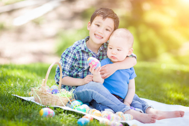 Vegyes Race kínai és kaukázusi fiúk kint a parkban játszik húsvéti tojás. - Fotó, kép