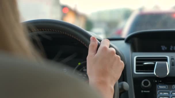 Achteraanzicht van de vrouwelijke bestuurder achter het stuur rijden een auto op een straat. - Video