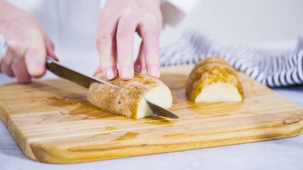 Βήμα-βήμα. Κόβουμε τις πατάτες σε φέτες με ελαιόλαδο και μπαχαρικά για να τις ψήσουμε στο φούρνο. - Φωτογραφία, εικόνα