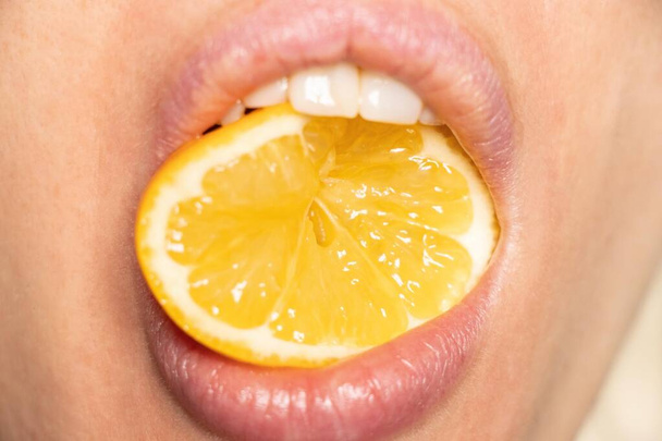 a slice of lemon in the girl's mouth close-up, there is a lemon - Photo, Image