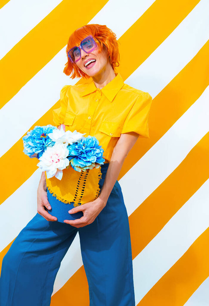 Vintage szczęśliwa dziewczyna na modnym pasiastym żółtym tle z układem kwiatów w jej rękach. Minimalna koncepcja wiosennego lata - Zdjęcie, obraz