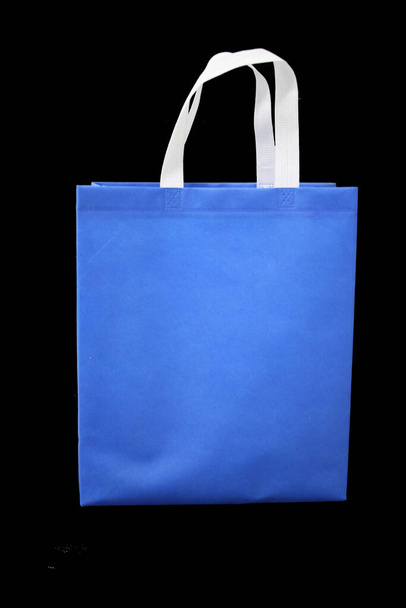 eco amigable bolsa de color azul con mango blanco sobre fondo negro, bolso no tejido, bolsa biodegradable, reducir, reutilizar, reciclar bolsa de compras - Foto, imagen