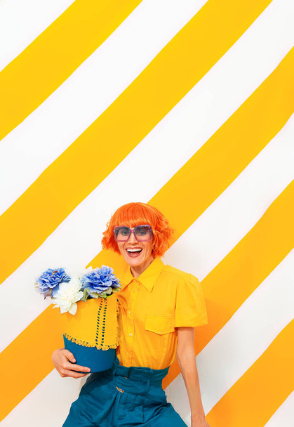 Vintage mosolygós lány divatos csíkos sárga háttér virágdísz a kezében. Minimális tavaszi nyári koncepció - Fotó, kép