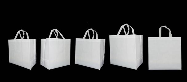 Набір нетканих білих тканин ручки циклу сумки на фоні чорного кольору. Не ткані сумки для покупок ECO. Біорозкладні сумки. Макетні
 - Фото, зображення