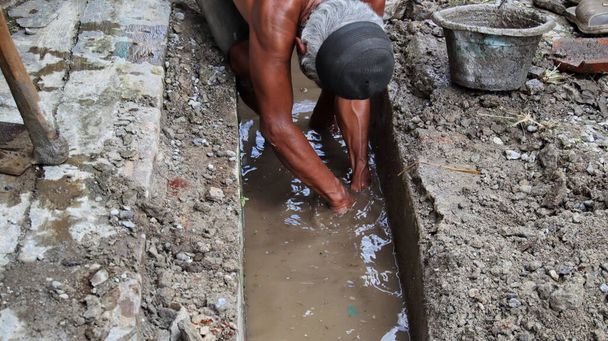 Selektives Fokusbild: Arbeiter säubern Abwasserkanäle vom verstopften Müll - Foto, Bild