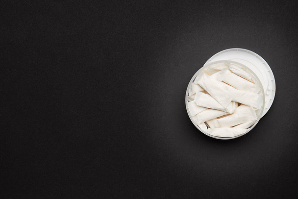 opened container with snus nicotine white bags on a dark background. copy space for design - Photo, Image